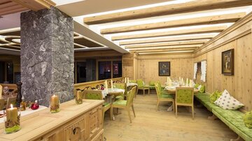 A cozy restaurant with wooden walls and green benches. The room is brightly lit and invites you to linger.