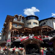 Ein gemütliches Restaurant mit Holzfassade und Terrassen. Blumen und Dekorationen verleihen der Ansicht einen einladenden Charme.
