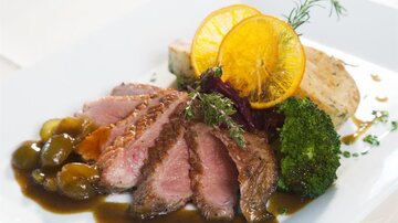 A delicious dish with tender meat, broccoli, and an orange slice. It is served with a fine sauce and various side dishes.