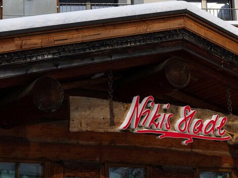 A traditional wooden building with a snow-covered roof. The sign reading "Nikis Stube" is clearly visible.