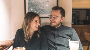 Ein lächelndes Paar sitzt in einem gemütlichen Café. Sie genießen einen entspannten Moment zusammen und trinken Cocktails.