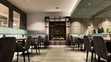 An elegant restaurant with modern furniture and soft lighting. The atmosphere is cozy and inviting.