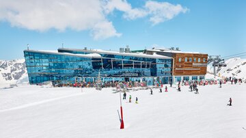 A modern mountain station surrounded by snow and mountains. Many people enjoy outdoor activities.