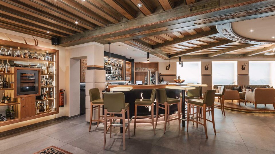 An elegant bar with a wooden ceiling and modern furnishings. Cozy seating and a well-stocked shelf give the atmosphere an inviting character.