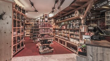 A tastefully decorated shop with shelves full of food and drinks. The space is warmly lit and has an inviting atmosphere.
