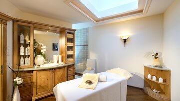 A relaxing spa area with a massage table and soft lighting. The room is bright and inviting, ideal for wellness treatments.