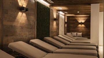 A relaxing wellness area with elegant loungers and warm light. The wooden walls create a cozy atmosphere.