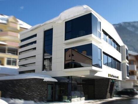A modern building with large windows and an elegant design. It is surrounded by snow, creating a winter atmosphere.