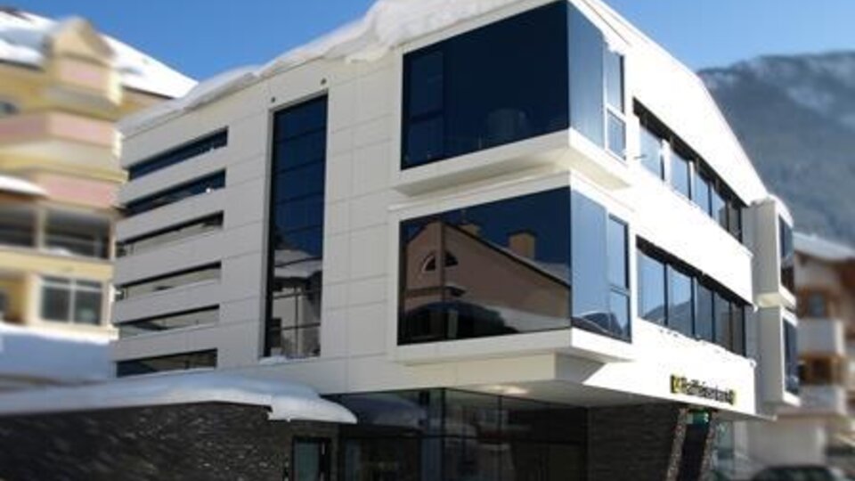 A modern building with large windows and an elegant design. It is surrounded by snow, creating a winter atmosphere.