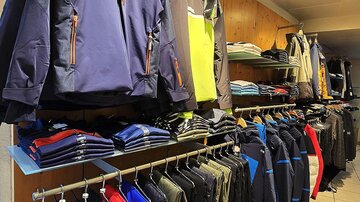 Ein Bekleidungsgeschäft mit verschiedenen Jacken und Shirts. Die Regale sind ordentlich mit Sport- und Outdoor-Bekleidung dekoriert.