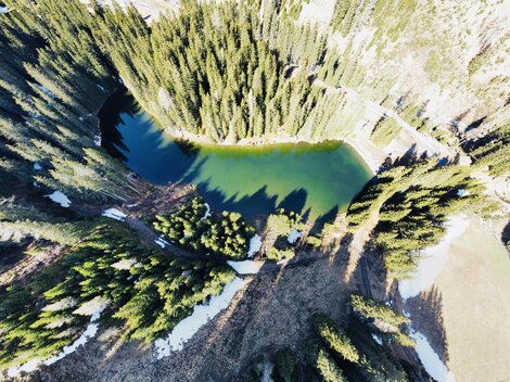 A picturesque lake surrounded by dense coniferous trees. The clear water surface reflects nature.