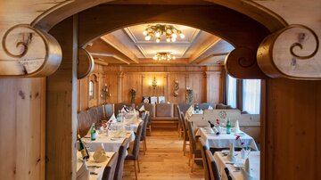 A cozy restaurant with wood interiors and elegantly set tables. Soft light illuminates the space and creates a relaxed atmosphere.