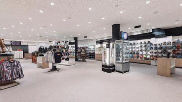 A modern retail store with clothing and accessories. The shelves are well organized and the space is brightly lit.