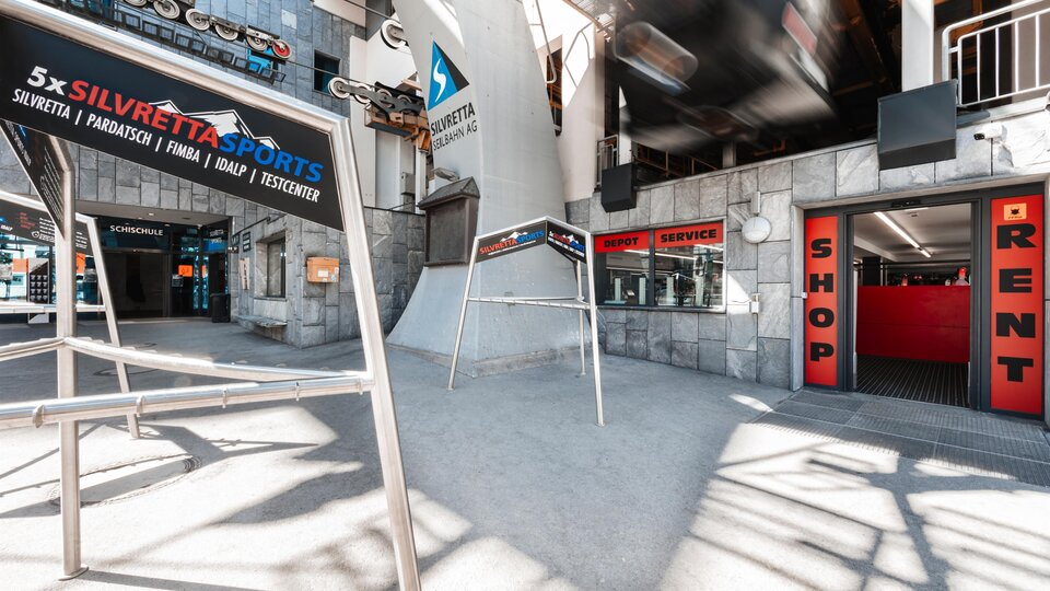 A modern sports store with display windows and an elegant appearance. In the background, signs with information about rentals and services can be seen.