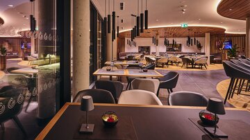 Ein modernes Restaurant mit stilvollen Möbeln und sanfter Beleuchtung. Die Atmosphäre ist einladend und elegant.