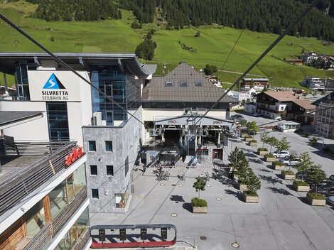 A modern lift area with a large building in the background. The surroundings are green and provide a cozy atmosphere.