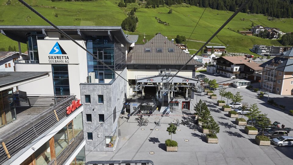 A modern lift area with a large building in the background. The surroundings are green and provide a cozy atmosphere.