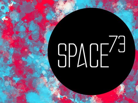 A striking, colorful background pattern in blue and red. The logo "SPACE73" in the center is black and has a modern design.