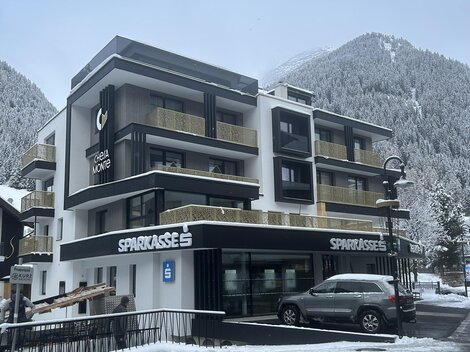Ein modernes Gebäude in einer schneebedeckten Landschaft. Die Architektur ist zeitgemäß mit großen Fenstern und einem klaren Design.