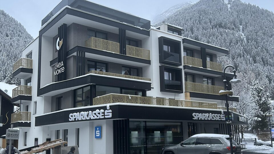 Ein modernes Gebäude in einer schneebedeckten Landschaft. Die Architektur ist zeitgemäß mit großen Fenstern und einem klaren Design.