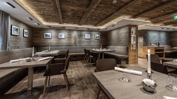 Ein modernes Restaurant mit Holzdecken und stilvollen Tischen. Die Einrichtung ist gemütlich und einladend.