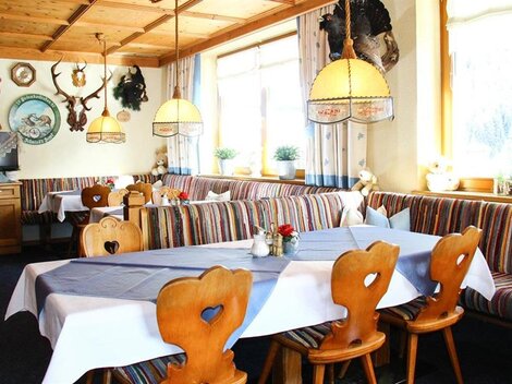 A cozy restaurant with wooden furniture and colorful benches. The room is bright and inviting, with decorative hunting trophies on the walls.