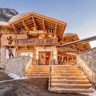 Ein charmantes alpenländisches Gebäude mit Holzstruktur und einem einladenden Eingangsbereich. Der Schnee rund um das Haus sorgt für eine winterliche Atmosphäre.
