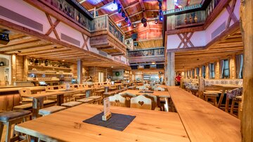 Ein rustikales Restaurant mit Holzinterieur und langen Tischen. Es ist hell und einladend, ideal für gesellige Treffen.