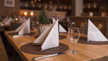 An elegantly set table in a restaurant. The table decoration includes folded napkins, glasses, and coasters.