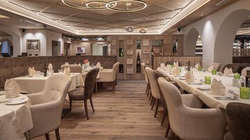 An elegant restaurant with modern furniture and soft lighting. The tables are beautifully set and invite you to linger.