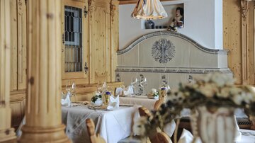 A cozy restaurant with wooden paneling and elegant table decorations. Soft light from the ceiling lamp creates an inviting atmosphere.