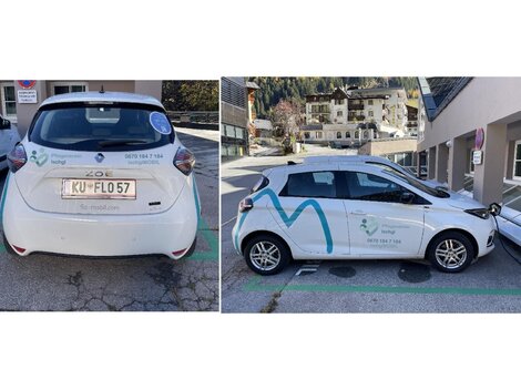 A white car with advertising on the side is parked in a city. The surroundings show residential buildings and a clean street.