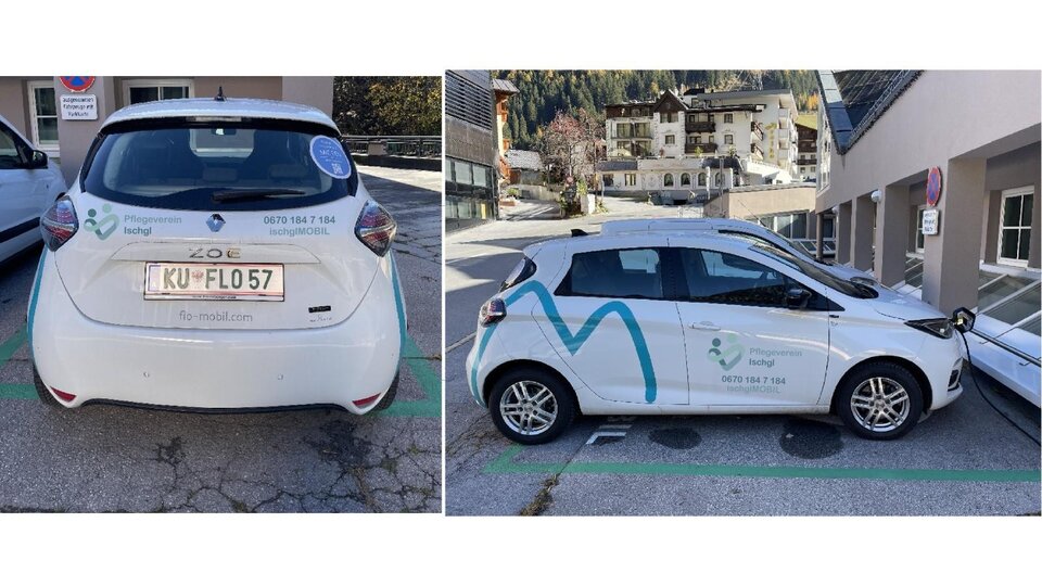 A white car with advertising on the side is parked in a city. The surroundings show residential buildings and a clean street.