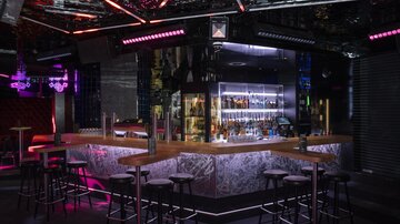 A stylish bar with modern lighting and a wide selection of drinks. The decor is elegant and inviting.