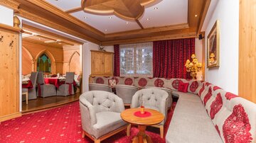 A cozy room with a round couch and a small table. The walls are adorned with wooden paneling and red accents.