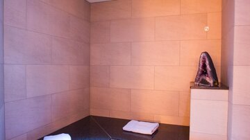 A relaxing interior with a sauna. A large amethyst sits on the stone and two towels are ready.