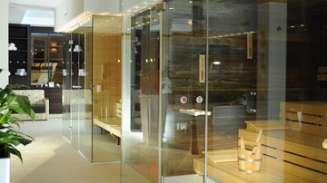 A modern wellness area with glass walls and wooden saunas. The atmosphere is relaxed and inviting.