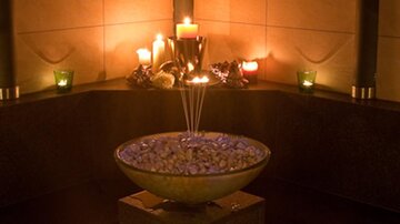 A stylish fountain with stones and gentle water flow in a serene environment. Candlelight creates a relaxing atmosphere.