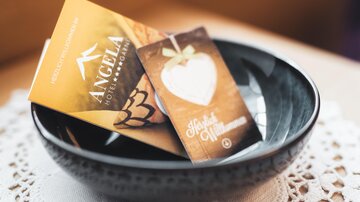 A black bowl with two cards inside. One card is from a hotel and the other is heart-shaped with a welcome message.