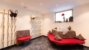 A modern room with red benches and appealing seating areas. The walls are equipped with decorative elements and a large window that provides natural light.