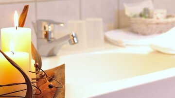 Eine entspannende Badewanne mit Kerzen und weichen Handtüchern. Die Atmosphäre ist ruhig und einladend.