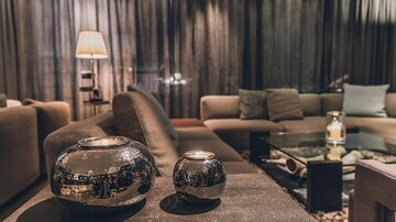 Ein stilvolles Wohnzimmer mit bequemen Sofas und moderner Dekoration. Auf dem Tisch stehen zwei dekorative Vasen und eine Kerze. | © elizabeth.at