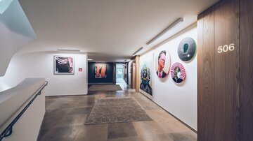 Ein moderner Flur mit Kunstwerken an der Wand. Am Ende des Flurs befindet sich eine Tür mit der Nummer 506. | © elizabeth.at