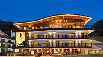 A modern hotel with a stylish facade and an arched roof. The lighting highlights the architecture at night.