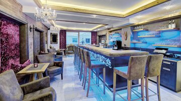An elegant bar with comfortable chairs and modern lighting. The space has an inviting atmosphere and stylish decoration.