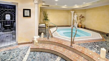 An elegant wellness area with a hot tub and stylish stone cladding. Soft lighting and decorative elements create a relaxing atmosphere.