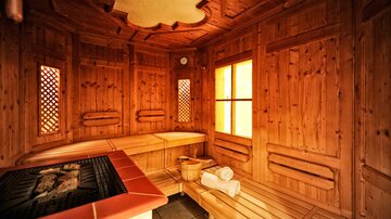 A cozy wooden sauna with benches and large windows. Gentle light streams in, creating a relaxed atmosphere.