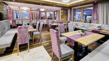 A modern restaurant with stylish tables and cozy seating areas. The atmosphere is bright and inviting, with large windows and elegant decoration.