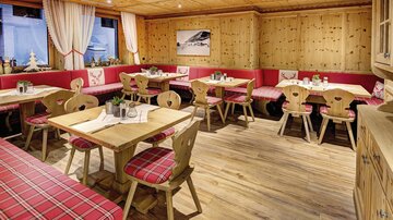 A cozy restaurant with wood-paneled walls and red benches. The tables are simply decorated, creating an inviting atmosphere.