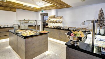 An elegant breakfast area with various dishes and fresh fruit. The facility is modern and well-organized, ideal for a pleasant meal.